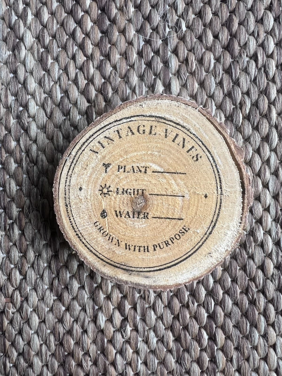 Close-up of a wood round stamped with plant, light, and water care details